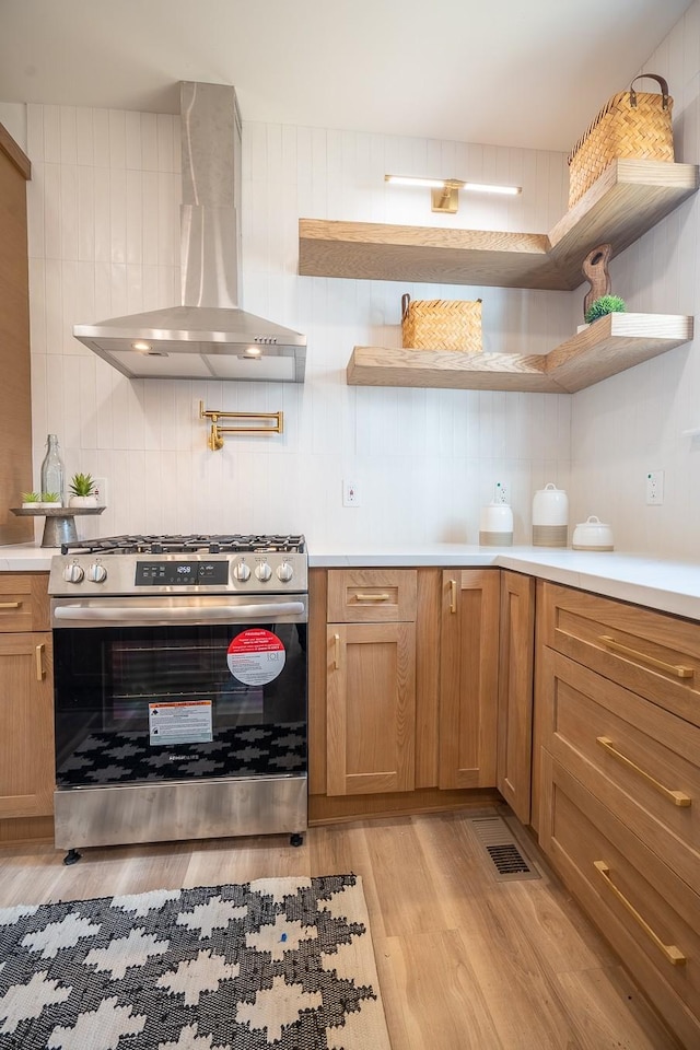 kitchen featuring gas range, extractor fan, decorative backsplash, and light wood-type flooring