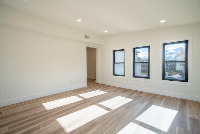 spare room with light hardwood / wood-style flooring and brick wall