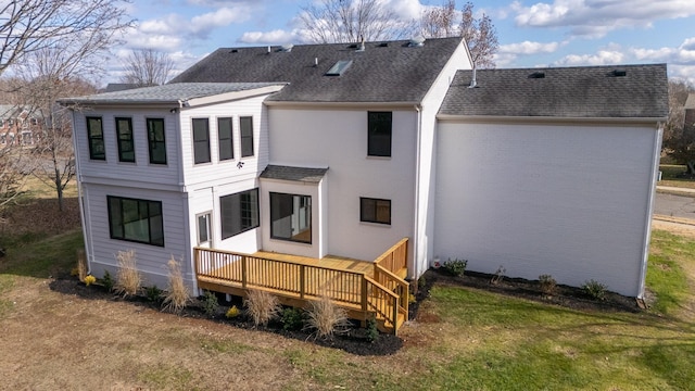 rear view of house featuring a wooden deck and a yard