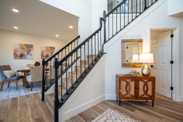 stairs featuring hardwood / wood-style floors and a towering ceiling