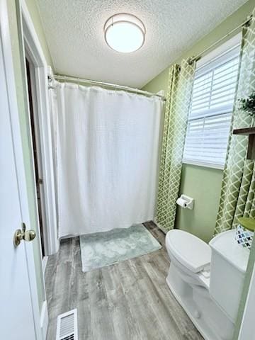 bathroom featuring hardwood / wood-style flooring, toilet, and a textured ceiling