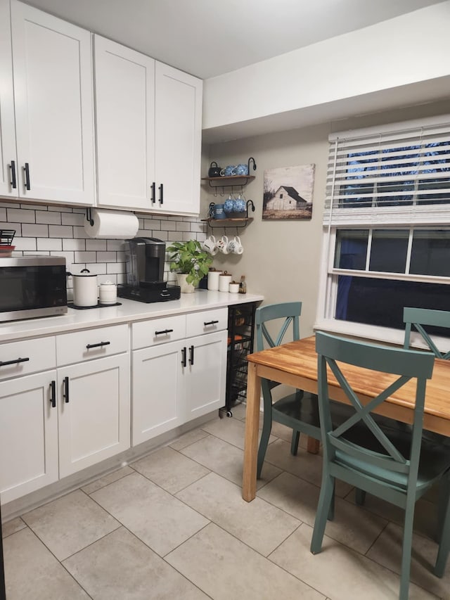 kitchen featuring tasteful backsplash, light tile patterned floors, and white cabinets