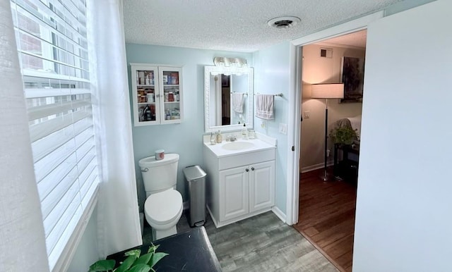 bathroom featuring vanity, hardwood / wood-style floors, a textured ceiling, and toilet