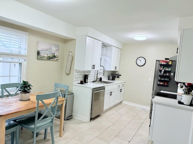 kitchen featuring white cabinetry, sink, backsplash, light tile patterned floors, and stainless steel appliances