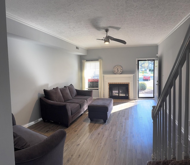 living room with a fireplace, wood-type flooring, ornamental molding, and a textured ceiling