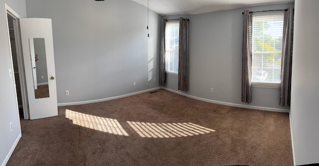 spare room featuring dark colored carpet and a textured ceiling