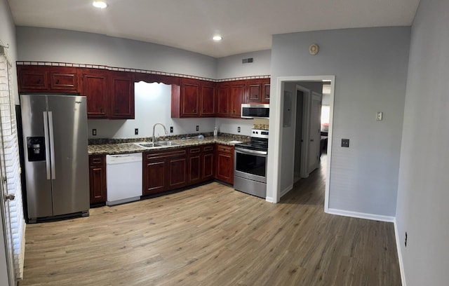 kitchen featuring stainless steel appliances, light hardwood / wood-style floors, sink, and stone countertops