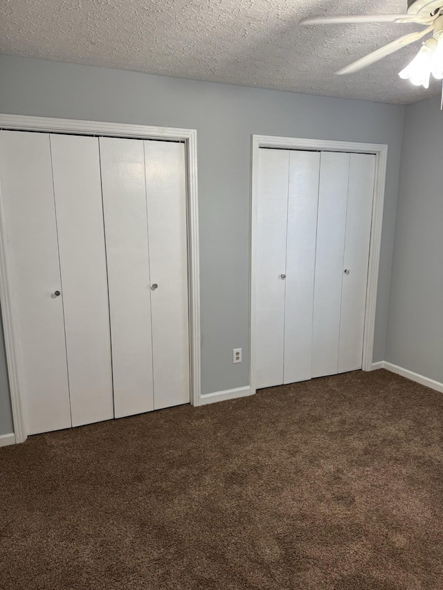 unfurnished bedroom with ceiling fan, a textured ceiling, carpet floors, and multiple closets