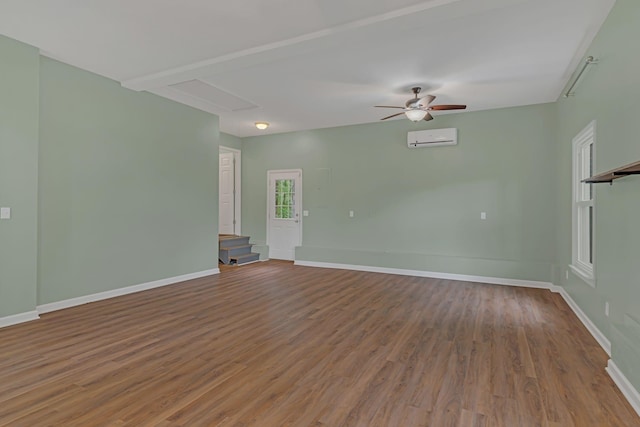 unfurnished room featuring ceiling fan, hardwood / wood-style flooring, beamed ceiling, and a wall mounted AC