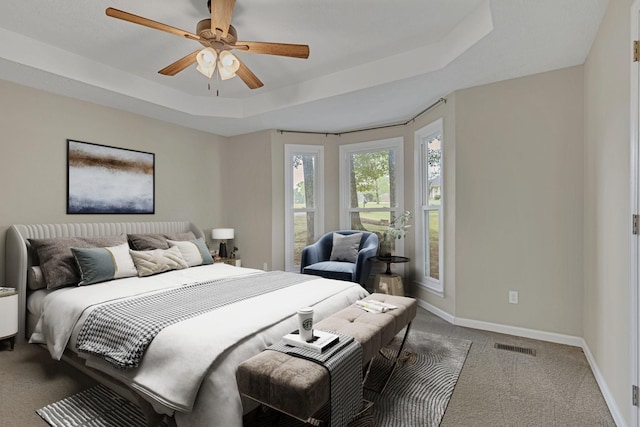 carpeted bedroom featuring ceiling fan and a tray ceiling