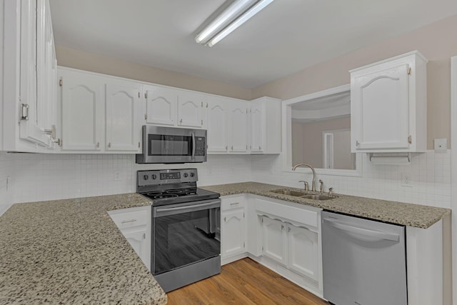 kitchen featuring sink, light wood-type flooring, white cabinets, stainless steel appliances, and backsplash