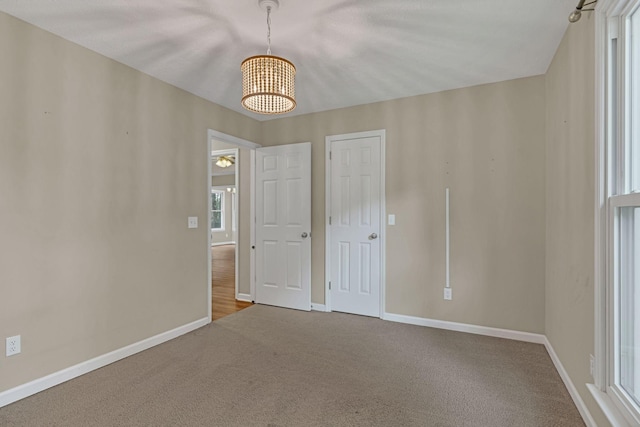 unfurnished bedroom with a chandelier and carpet