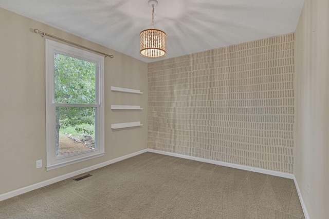 carpeted empty room featuring a notable chandelier