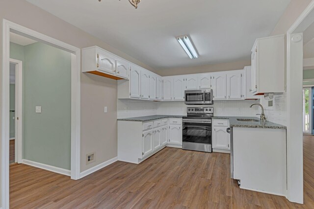 kitchen featuring sink, white cabinetry, stone countertops, light hardwood / wood-style flooring, and stainless steel appliances