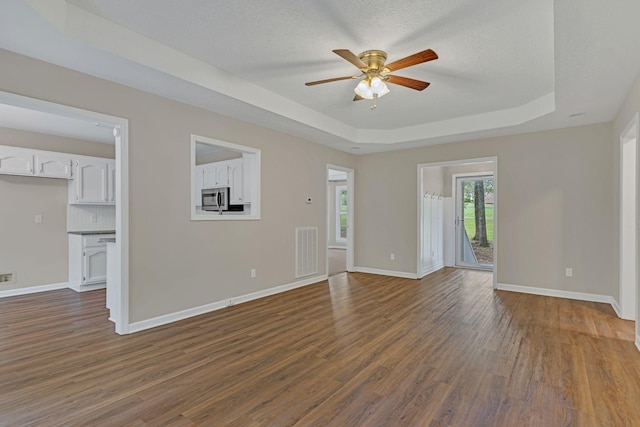 spare room with dark hardwood / wood-style floors, a textured ceiling, ceiling fan, and a tray ceiling