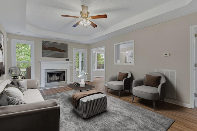 living room with a healthy amount of sunlight, hardwood / wood-style floors, and a tray ceiling