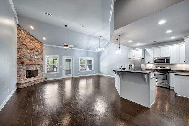 kitchen with white cabinetry, stainless steel appliances, an island with sink, and a breakfast bar area