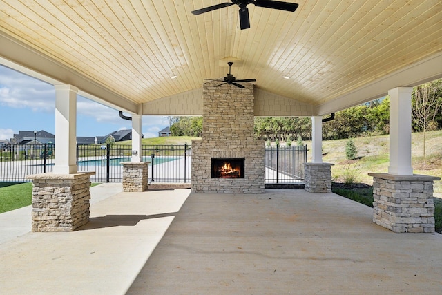 view of patio with a fenced in pool, ceiling fan, and an outdoor stone fireplace