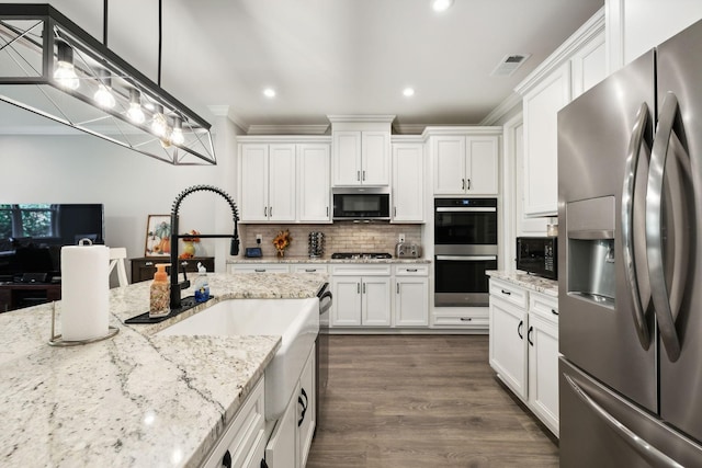 kitchen featuring appliances with stainless steel finishes, light stone countertops, decorative backsplash, white cabinets, and decorative light fixtures