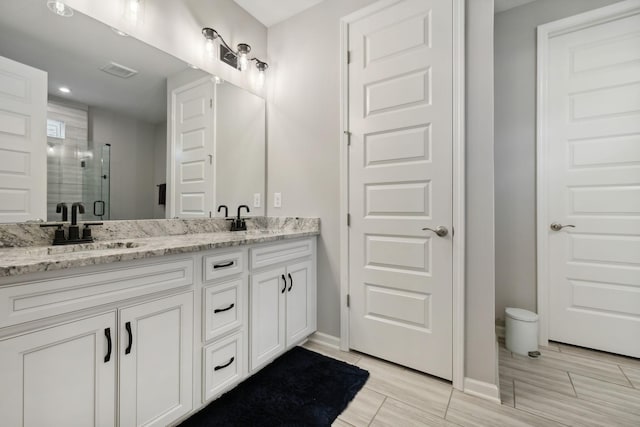 bathroom featuring vanity and a shower with door