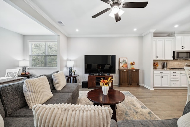 living room featuring crown molding, ceiling fan, and light hardwood / wood-style floors