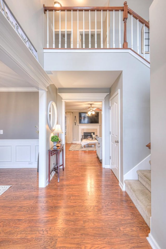 entryway with hardwood / wood-style flooring, ornamental molding, and a towering ceiling