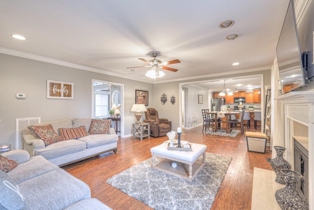 living room featuring ceiling fan, ornamental molding, wood-type flooring, and a fireplace