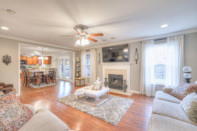 living room featuring crown molding, a healthy amount of sunlight, and light wood-type flooring