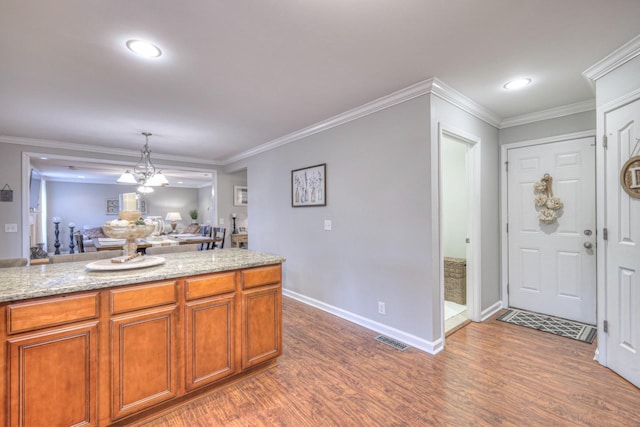 kitchen with crown molding, light stone countertops, and dark hardwood / wood-style floors