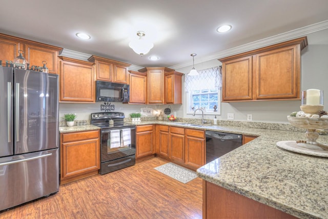 kitchen with sink, hanging light fixtures, ornamental molding, black appliances, and light wood-type flooring