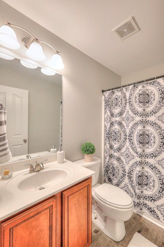 bathroom featuring vanity, toilet, curtained shower, and hardwood / wood-style floors