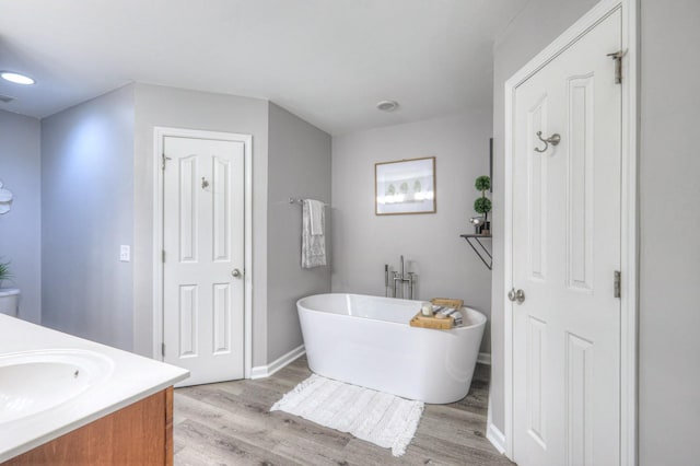 bathroom with hardwood / wood-style flooring, vanity, and a tub