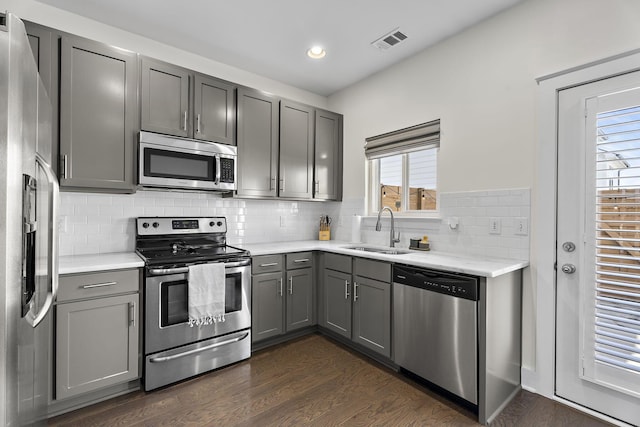 kitchen with appliances with stainless steel finishes, sink, gray cabinetry, and dark hardwood / wood-style floors