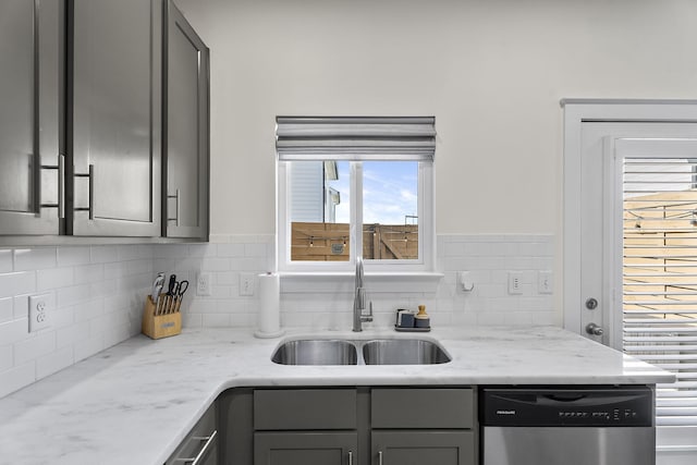 kitchen with sink, gray cabinets, stainless steel dishwasher, and light stone countertops