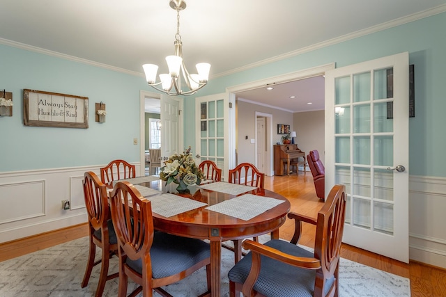 dining space with an inviting chandelier, light hardwood / wood-style flooring, and ornamental molding