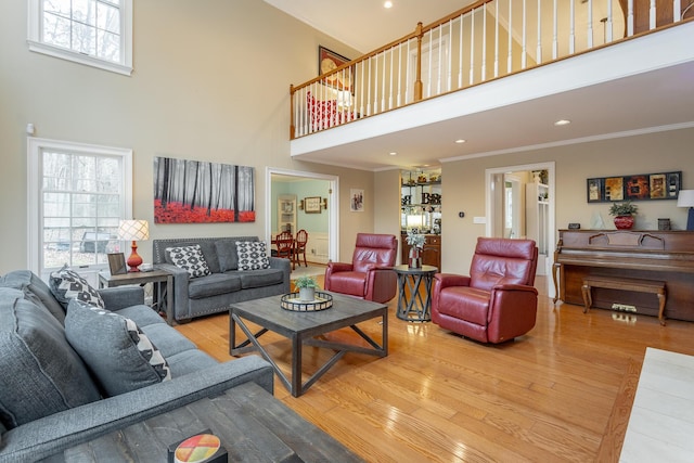 living room with hardwood / wood-style floors, crown molding, plenty of natural light, and a high ceiling