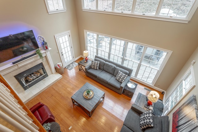 living room featuring a towering ceiling, plenty of natural light, a fireplace, and hardwood / wood-style floors