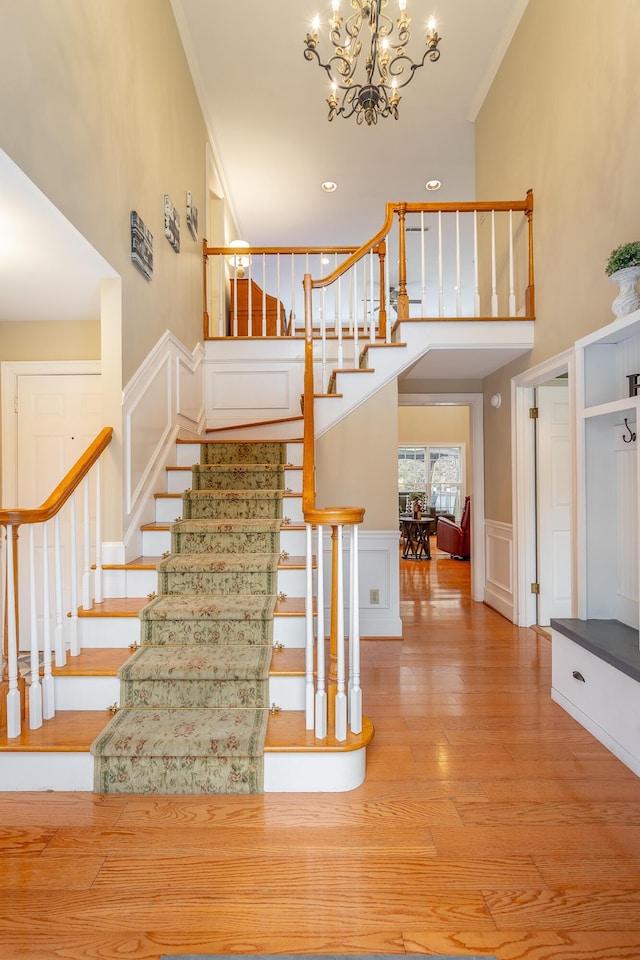 stairs featuring a notable chandelier, wood-type flooring, and ornamental molding