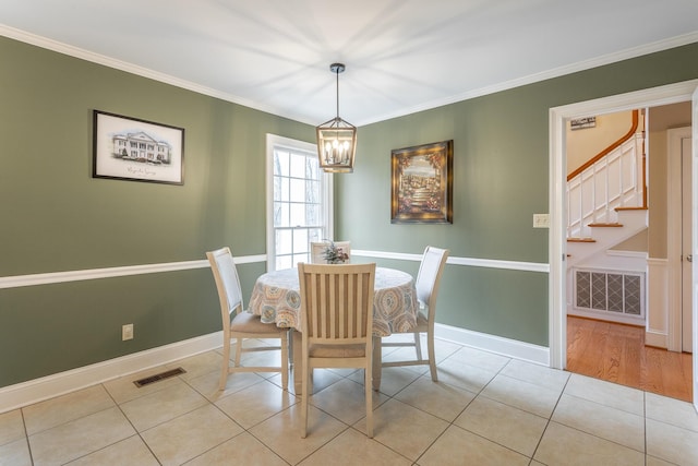 tiled dining room with crown molding and a chandelier