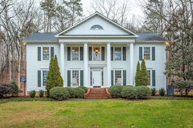 neoclassical home featuring a front lawn