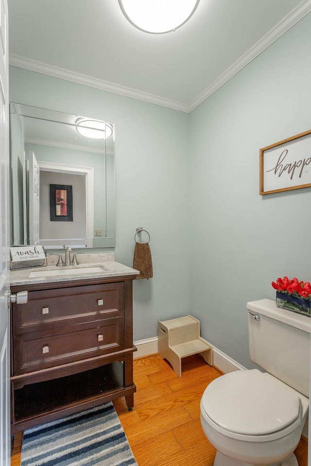 bathroom with hardwood / wood-style flooring, vanity, crown molding, and toilet