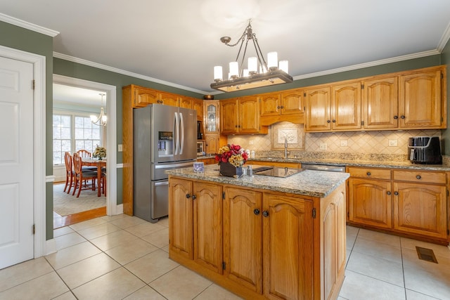 kitchen with pendant lighting, crown molding, stainless steel appliances, a kitchen island, and a chandelier