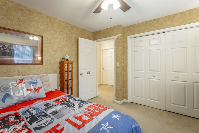 bedroom featuring light colored carpet, ceiling fan, and a closet