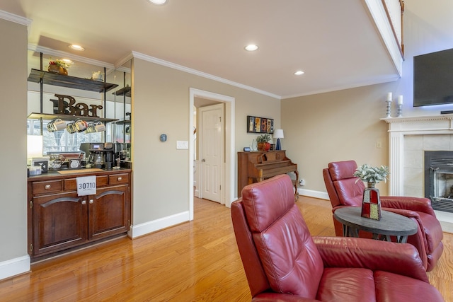 living room with crown molding, a fireplace, and light hardwood / wood-style floors