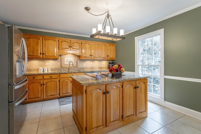 kitchen featuring pendant lighting, sink, stainless steel fridge, ornamental molding, and a center island