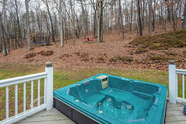 deck with an outdoor hot tub and a trampoline