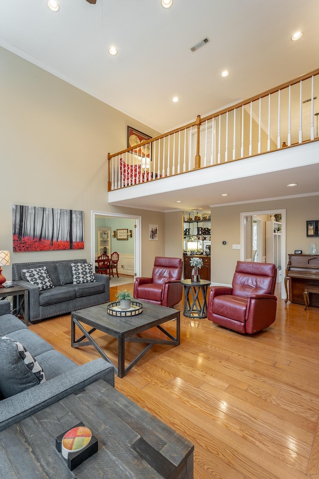 living room featuring a towering ceiling, ornamental molding, and hardwood / wood-style floors