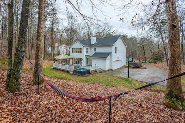 rear view of property with a wooden deck and a garage