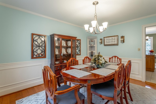 dining room with an inviting chandelier, crown molding, and light wood-type flooring