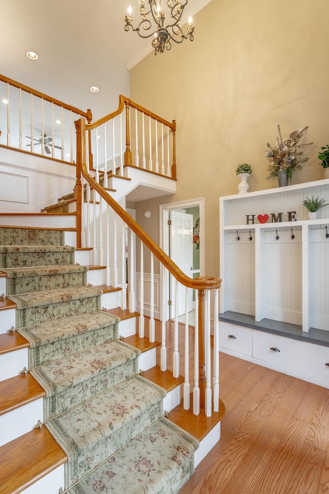 staircase featuring hardwood / wood-style flooring, a high ceiling, and an inviting chandelier